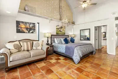 The master bedroom is spacious and airy, featuring a cozy couch near the wide window that frames breathtaking views of the lake, an ideal retreat for rest and relaxation.