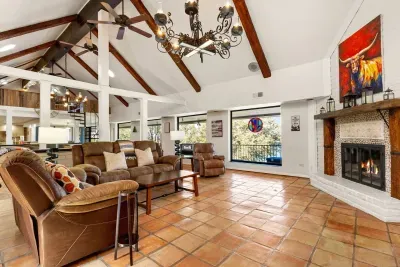 Relax in the spacious living room with a cozy fireplace and wide couch, framed by tall windows overlooking the pool and Canyon Lake from the balcony.
