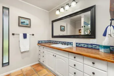 This full bathroom offers all the essentials, including a spacious shower, vanity with ample counter space, and fresh white and blue accents that complement its rustic charm.