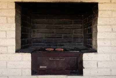 A charcoal grill nestled under rustic clay blocks, perfect for authentic smoky BBQ and cozy outdoor cooking.