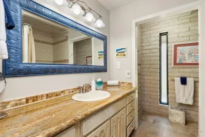 This full bathroom offers all the essentials, including a spacious shower, vanity with ample counter space, and fresh white and blue accents that complement its rustic charm.