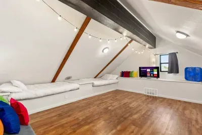 The attic loft features double beds on each side, a TV, and a wide open floor, perfect for fun sleepovers, storytelling, or laid-back movie nights.