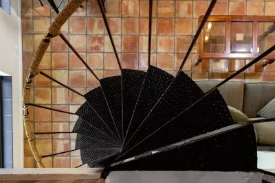 A rustic steel spiral staircase leads up to the attic loft, adding character and a touch of vintage charm to the space.