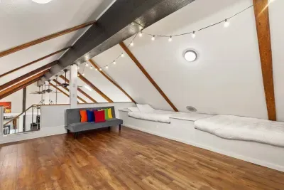 The attic loft features double beds on each side, a TV, and a wide open floor, perfect for fun sleepovers, storytelling, or laid-back movie nights.