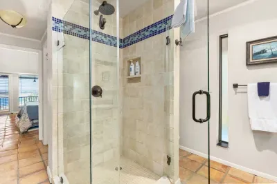This full bathroom offers all the essentials, including a spacious shower, vanity with ample counter space, and fresh white and blue accents that complement its rustic charm.