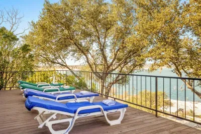 A peaceful spot featuring lounge chairs with a relaxing view of lush trees and the shimmering lake beyond.