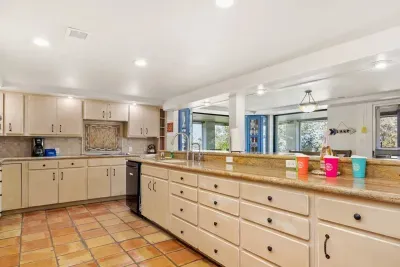 Enjoy meal prep at the kitchen’s island counter, where wide windows frame stunning views of the lake, blending function with a peaceful backdrop.