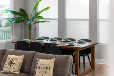 Bright dining area with seating for the whole group, surrounded by large windows and coastal décor—perfect for family meals, game nights, or planning the day’s adventures.