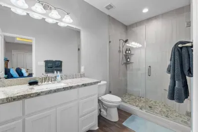 Modern, spa-style bathroom featuring a large vanity with plenty of storage, bright lighting, and a spacious glass walk-in shower with coastal-inspired finishes—ideal for getting ready comfortably as a group.