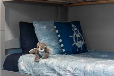 Cozy coastal bunks your kids will LOVE  This twin bed is dressed in beachy bedding with fun nautical pillows—perfect for little ones to relax, watch a movie, or crash after a full day of sand + sunshine!