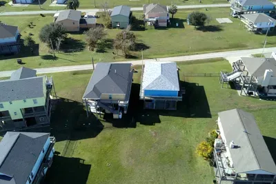Bird’s-eye view showing the home’s layout, open yard space, and the quiet neighborhood setting—perfect for a relaxing beach getaway with room to spread out.