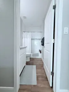 Bright, clean, and spacious bathroom with a tub/shower combo, plenty of counter space, and fresh coastal finishes—perfect for rinsing off after a day at the beach.