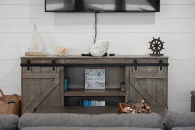 Unwind in the living room with a big-screen TV and coastal decor—perfect for movie nights after a day at the beach.