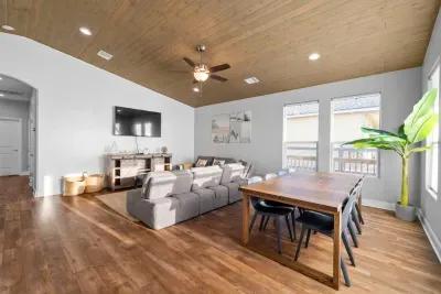 Bright, open living space with a vaulted wood ceiling, comfy sectional, and a large dining table—perfect for relaxing after the beach or gathering everyone for meals and game night.