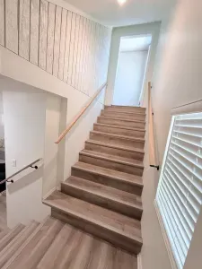 Beautiful wooden stairs lead you to the upper level, blending rustic charm with modern elegance right in the heart of the living space.