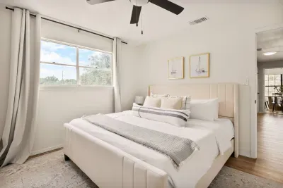 Conveniently located just steps from the dining area, this cozy bedroom features a spacious bed, soft cream-white décor, and a large window that fills the room with natural light, perfect for restful nights and easy access to morning meals.