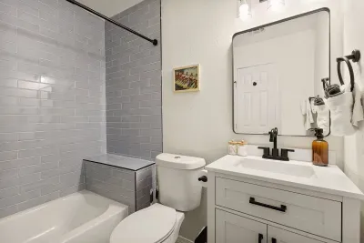 This bright, inviting bathroom features a sink, toilet, and a shower-tub combo, perfect for quick refreshes or a relaxing soak after a day of adventures