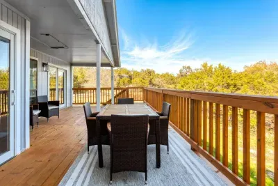 Enjoy meals or morning coffee on the spacious wraparound deck, featuring a stylish outdoor dining set and serene views of the surrounding treetops. This inviting space is perfect for dining, relaxing conversations, or soaking in the peaceful setting.