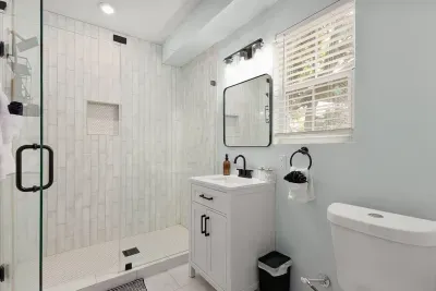Spa-inspired bathroom featuring a spacious glass walk-in shower with rainfall head, elegant tile walls, and built-in bath products. Modern vanity, soft towels, and bright natural light create a fresh and relaxing retreat.