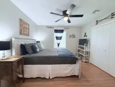 The master bedroom is furnished with a comfortable queen-sized bed and a ceiling fan for added comfort. Extra linens, blankets, and an additional fan can be found in the closet.