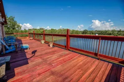 The massive upper deck boasts stunning red-stained wood and railings, offering an incredible panoramic view of the stocked pond and surrounding acreage. Adirondack chairs invite you to relax and soak up the Texas sun and tranquil scenery.