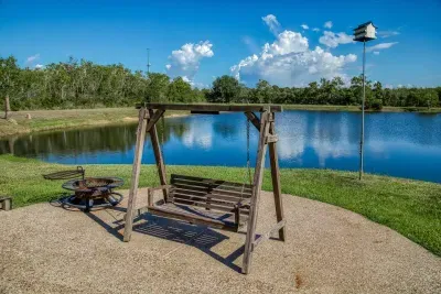 Relax and enjoy the view! This dedicated outdoor area features a charming wooden porch swing and a fire pit, all set against the backdrop of the large, tranquil stocked pond. The perfect spot for morning coffee or an evening under the stars.