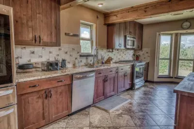 Our fully equipped kitchen boasts granite counters, wood cabinets, and all stainless steel appliances, including a dishwasher. Large windows overlook the scenic property, ensuring you have everything you need for meal preparation with a view.