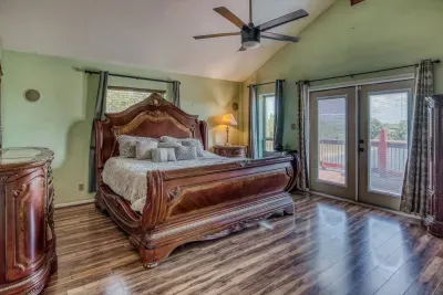 Indulge in the luxurious Master Bedroom, featuring a stately, carved King bed and elegant furniture. Enjoy high vaulted ceilings with a fan, wood-look flooring, and French doors that open directly to the outdoor deck for easy access and scenic views.