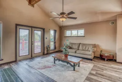 Discover our inviting upstairs living room, featuring a comfy sofa, elegant decor, and direct French door access to the oversized deck. With high ceilings and a ceiling fan, it's a bright, airy space perfect for relaxing and enjoying the views.