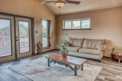 Discover our inviting upstairs living room, featuring a comfy sofa, elegant decor, and direct French door access to the oversized deck. With high ceilings and a ceiling fan, it's a bright, airy space perfect for relaxing and enjoying the views.