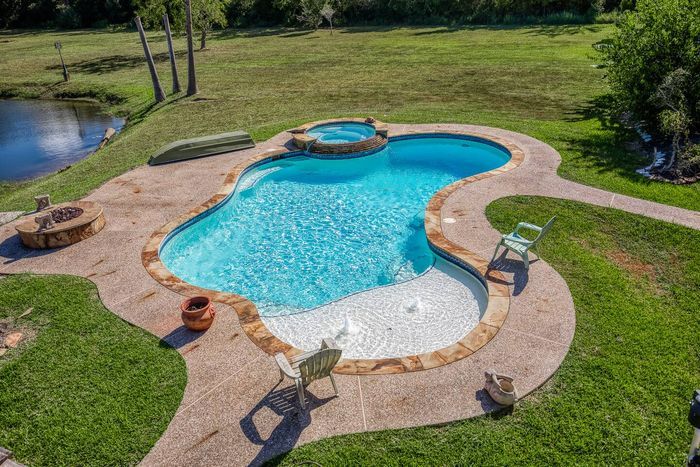 Your private escape! Dive into the crystal-clear pool or relax in the stone-clad tub. The stunning two-story home features an oversized upper deck and covered patio by the pool, surrounded by 5 acres of tranquility.