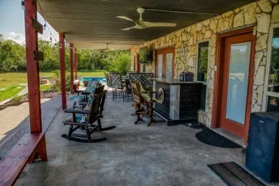 The extensive covered patio offers multiple seating areas, including rocking chairs & a bar-height table. Enjoy the fresh air while staying cool with ceiling fans. Access indoors through the doors, or walk right out to the pool & the expansive yard!