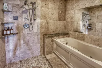 Indulge in the Master Bathroom's luxurious jacuzzi tub and expansive walk-in tiled shower with a dual head system. Elegant natural stone tile creates a serene, spa-like atmosphere for ultimate relaxation.