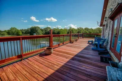 The massive upper deck, stained a deep red, runs the full width of the house, offering unparalleled panoramic pond views. Relax on the Adirondack chairs and enjoy the expansive space and gorgeous Texas scenery.
