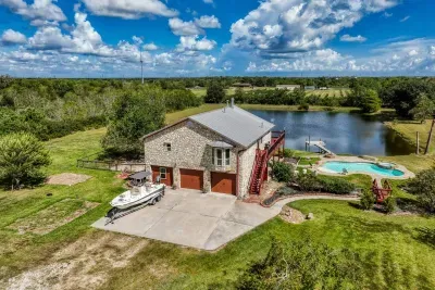 This stunning aerial view highlights the entire property: the handsome stone home with a two-car garage, large driveway (perfect for boat parking), private swimming pool, and a stocked pond with its own pier. Enjoy the complete 5-acre retreat!