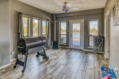 Get your grill on! This bright sunroom holds the pellet grill, ready for your BBQ masterpiece. It offers wood-look tile floors and a direct walk-out to the deck, all while overlooking the stocked pond.