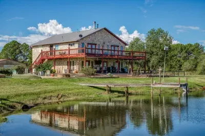 The ultimate waterfront view! The beautiful stone house boasts a huge two-level deck and a patio for outdoor living. Directly in front is the fishing pier on the edge of the stocked pond, offering endless opportunities for fun and relaxation.