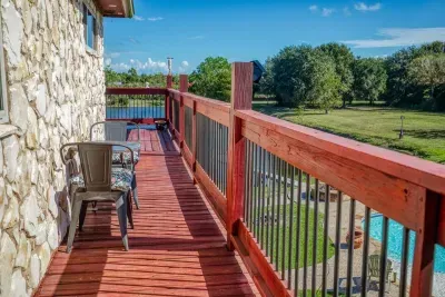 Enjoy morning coffee on the upper deck with its vibrant red railing. This relaxing spot offers a small bistro set and fantastic views of the stocked pond, private pool, and the large 5-acre property below.