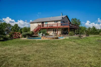 Cool off in the private swimming pool! The pool area, with stone coping and sun loungers, sits perfectly below the main house. Enjoy the massive two-story deck and covered patio overlooking the large grassy yard on our 5-acre retreat.