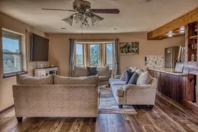 Enjoy our open, cozy living area, featuring plush sofas, a large wall mounted Smart TV, and a ceiling fan for comfort. The space flows into the built-in bar area with a mini-fridge, perfect for social gatherings and relaxing with family and friends.