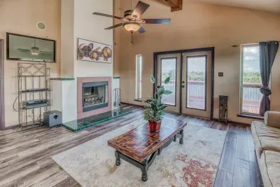 Relax in the upstairs living room with a cozy fireplace, TV entertainment area, and a ceiling fan. French doors lead directly to the deck, offering great views of the 5-acre retreat.