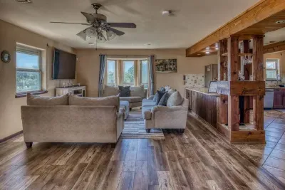 Enjoy our open, cozy living area, plush sectional sofas, a large wall-mounted Smart TV, and a ceiling fan for comfort. The space flows into the built-in bar area with a mini-fridge, perfect for social gatherings and relaxing with family and friends.