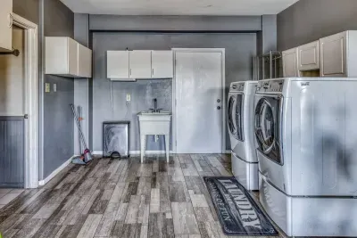 Convenient and spacious, the laundry room is equipped with modern full-sized washer and dryer units. It includes a utility wash sink, storage cabinets, and stylish wood-look flooring to make laundry a breeze.
