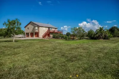 Enjoy the vast 5-acre property, featuring an enormous grassy yard perfect for family and pet play! The handsome stone-clad house offers a large two-story deck and ample space to park a boat (seen on the left) for easy access to Galveston Bay.