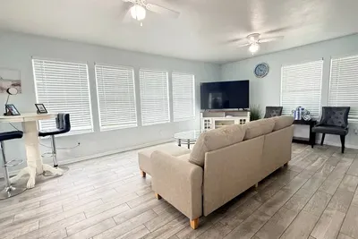 Spacious living room with a large sectional, big-screen TV, and plenty of seating—perfect for movie nights, game time, and relaxing after the beach.