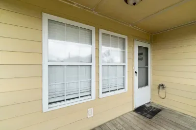 Cozy covered entryway with large windows and a classic white door.