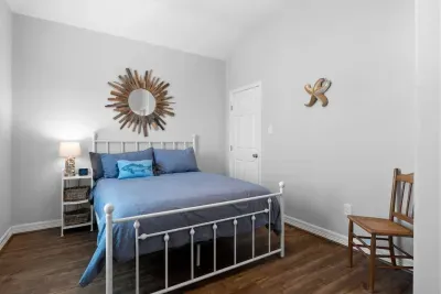 Relax in this charming second bedroom! The white metal bed and cozy blue bedding create a perfect coastal retreat, accented by a striking sunburst mirror and nautical decor. Convenient storage is found in the wicker basket nightstand.