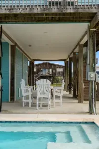 Perfect for poolside lounging! This covered patio sits right next to the Pool. Relax on the white Outdoor furniture  and enjoy the coastal air in the shade, just steps away from a refreshing dip.