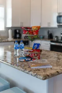This close-up showcases the thoughtful welcome on the kitchen's granite island! Complimentary bottled water and snacks are offered alongside the Guest Book, providing a perfect, inviting start to your stay at "At Last."