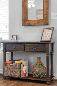 This stylish wooden console serves as your welcoming guest hub! It conveniently displays helpful information and holds a basket filled with books and games  for all ages, adding coastal charm to the living area.